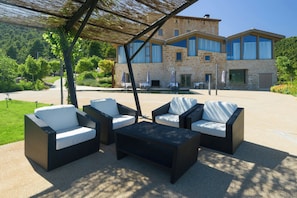 Zona relax esterna con mobili in vimini e piscina.