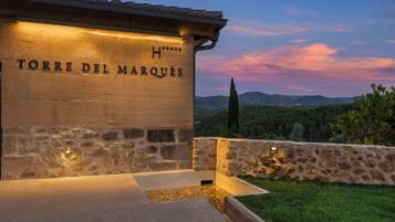 Un edificio de piedra con el letrero 'TORRE DEL MARQUES', una pared de piedra y vistas al paisaje.