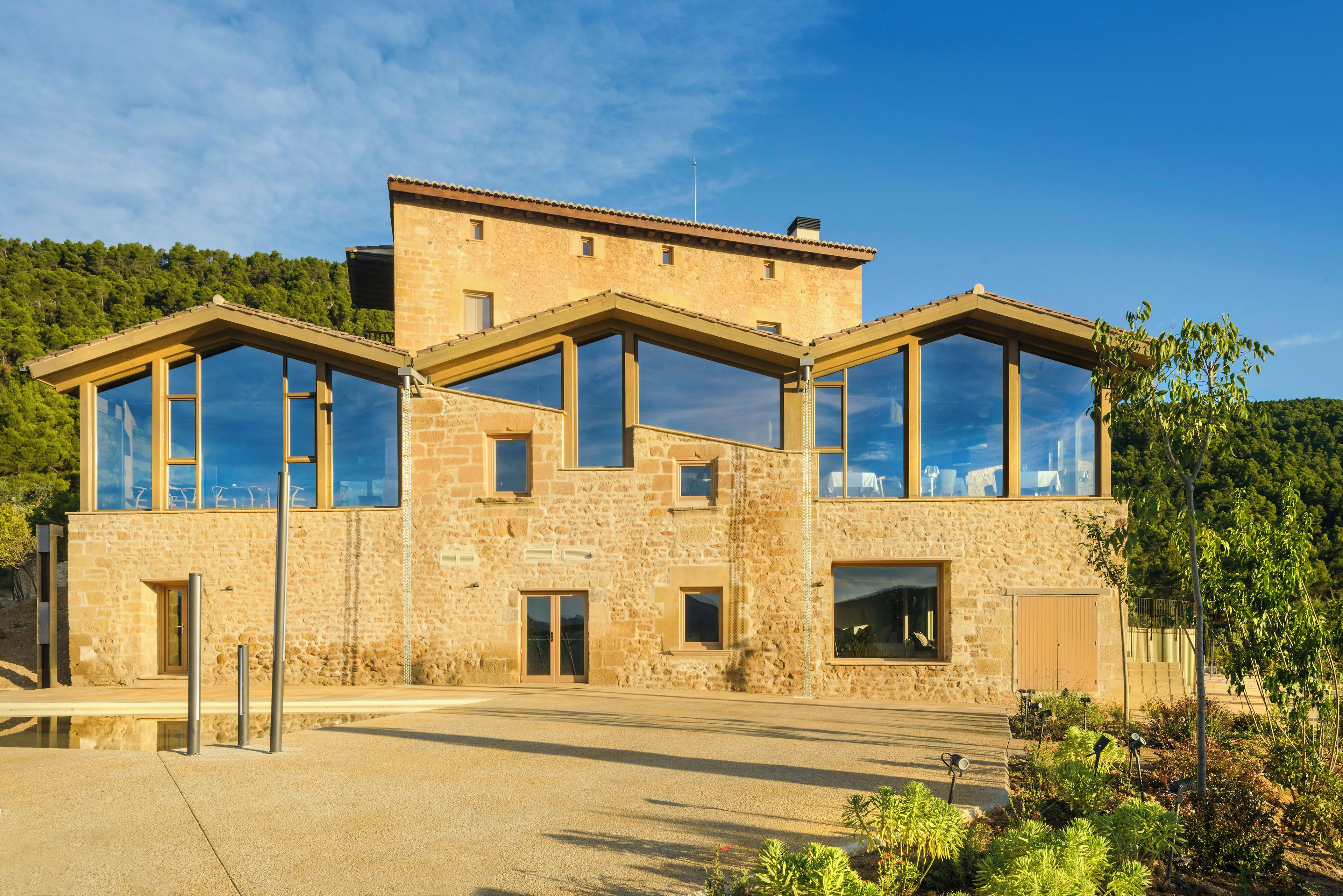 Un edifici de pedra de dues plantes amb finestres grans i teulada plana.
