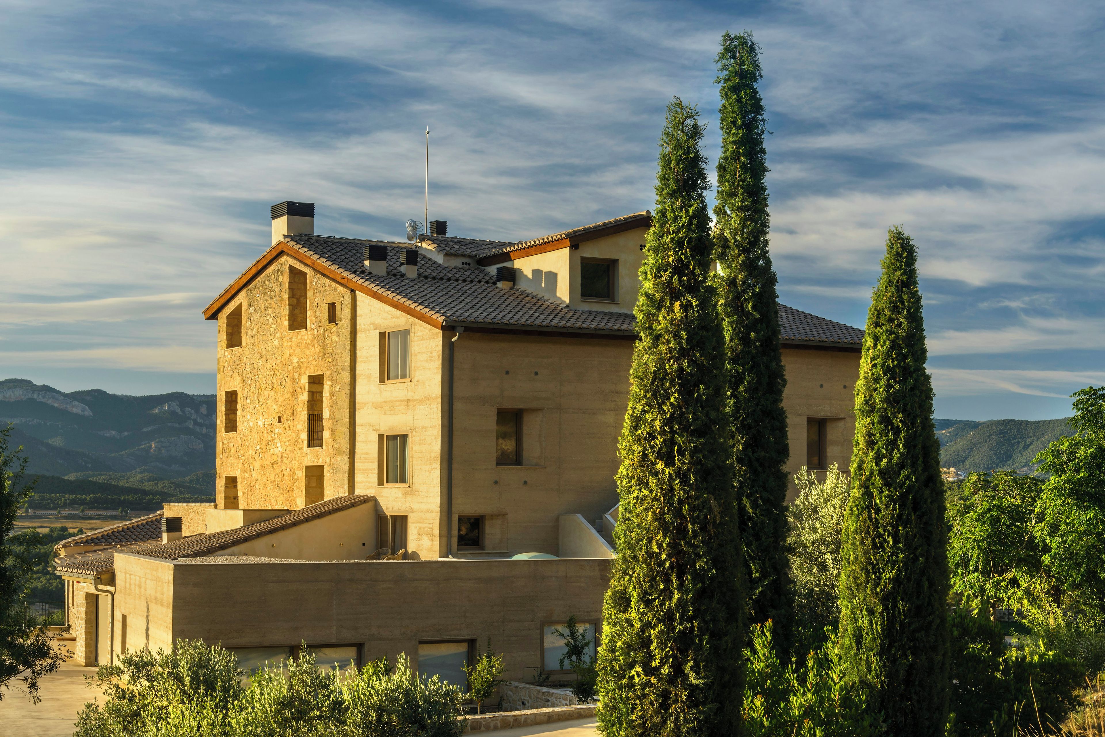 A two-story building with a stone facade, multiple windows, and a flat roof.