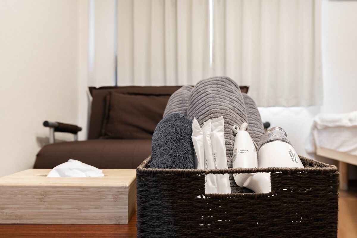 A wicker basket on a bedside table containing toiletries and a tissue box.
