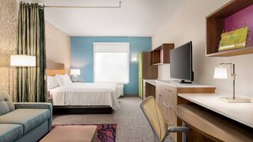 A hotel room with a bed, a desk, a chair, a television, and a window.