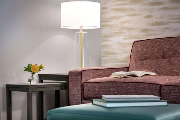 Una habitación moderna con un sofá, una mesa con un jarrón de flores y una lámpara de pie.
