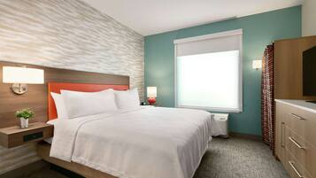 Quarto de hotel com cama, mesas de cabeceira, televisão e janela com cortinas.