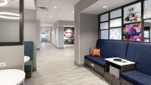 Un hall d’hôtel moderne avec un espace salon, un comptoir d’accueil et, au fond, une enseigne indiquant « Friandises ».