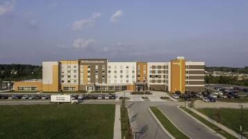 A hotel with multiple floors, a parking lot, and a green lawn area.