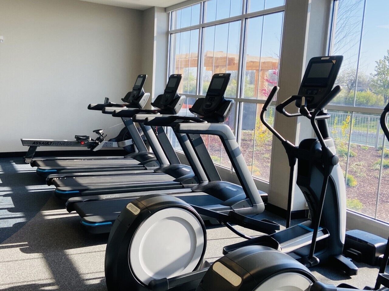Varias bicicletas estáticas en un gimnasio con amplias ventanas.
