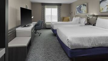 Habitación de hotel con una cama grande, un escritorio, un televisor de pantalla plana, una silla y una ventana con cortinas.