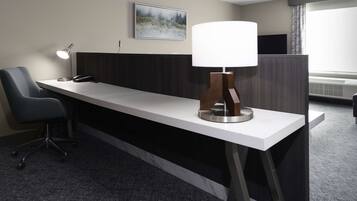 Un mostrador de recepción de hotel con una lámpara moderna, un teléfono y una silla.
