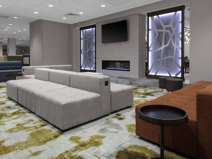 A modern living room with a sectional sofa, a fireplace, and a flat-screen TV mounted on the wall.