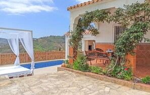 A patio with a pool, a covered seating area, and a view of the hills.