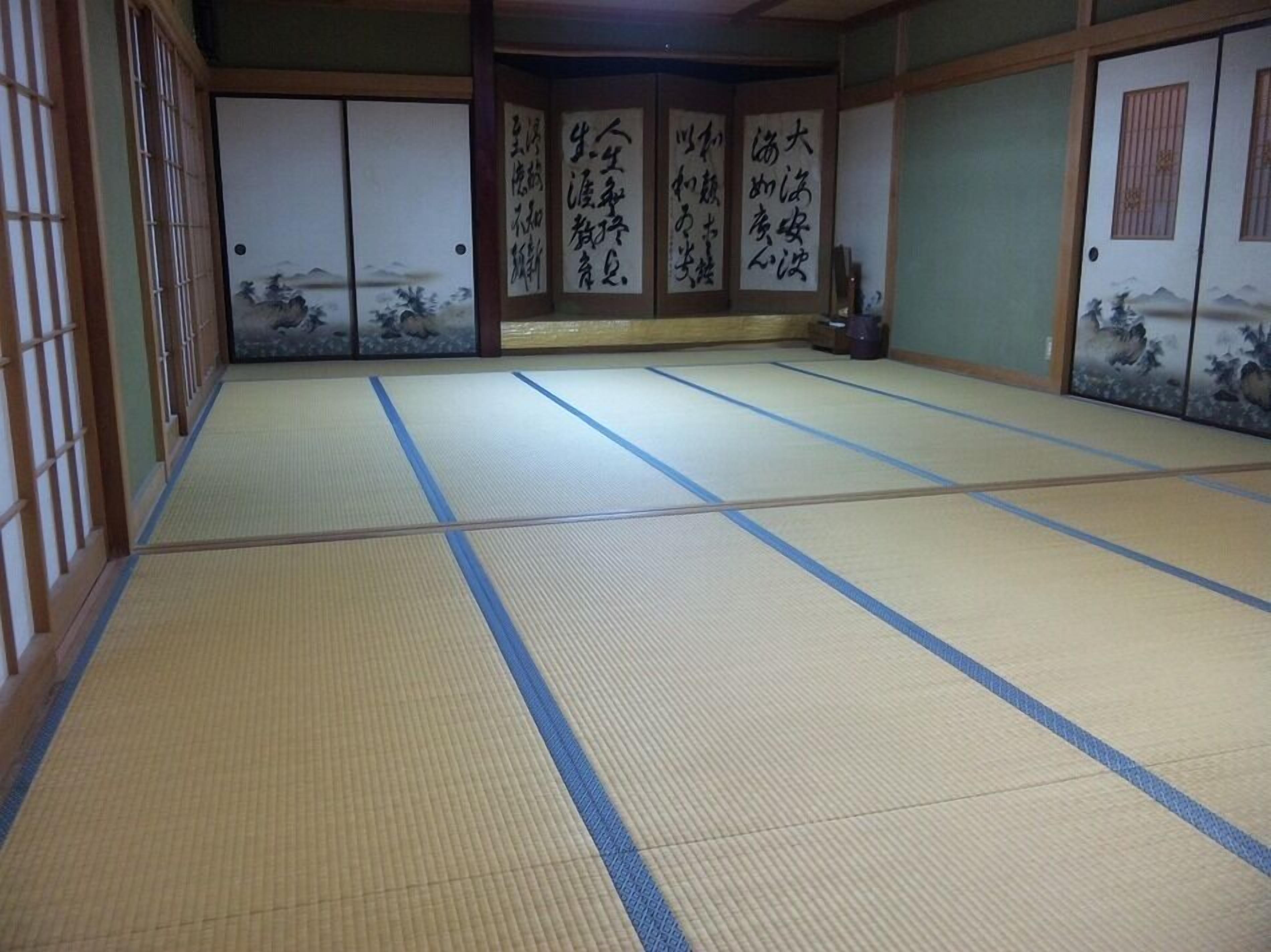 A tatami mat room with sliding doors, a traditional Japanese aesthetic, and calligraphy on the doors.