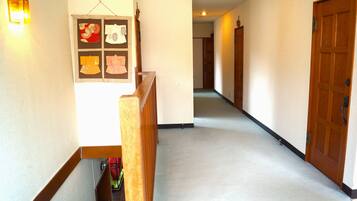 Un pasillo con barandilla de madera, una lámpara de pared y una puerta al final.