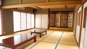 A traditional Japanese room with tatami flooring, a low wooden table, sliding doors, and calligraphy on the walls. - Resort Pension Turtle House (Shimoda)
