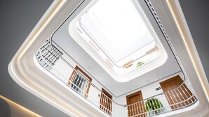 A multi-level atrium with a central skylight, balconies with railings, and a modern architectural design. - Plazuela del Carbón Suites (Cádiz)