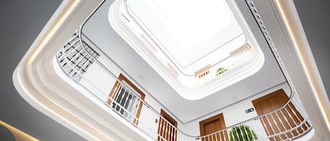 A multi-level atrium with a central skylight, balconies with railings, and a modern architectural design.