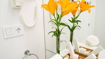 A bathroom with a white sink, a mirror, a telephone, and a wooden tray with toiletries.