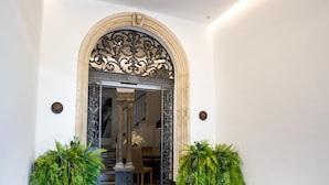 A modern hotel lobby with a marble floor, a wooden reception desk, and decorative plants. - Plazuela del Carbón Suites (Cádiz)