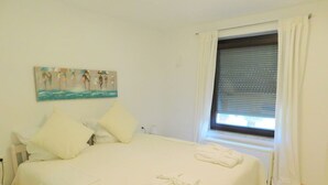 A bedroom with a bed, pillows, a painting, a window with curtains, and a towel on the bed. - Private apartment Angelika NEW (Lorch)