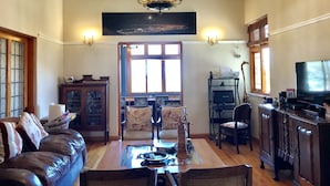A spacious living room with a chandelier, a fireplace, a large window, and a television. - Redbourne Hilldrop B&B (Cape Town)