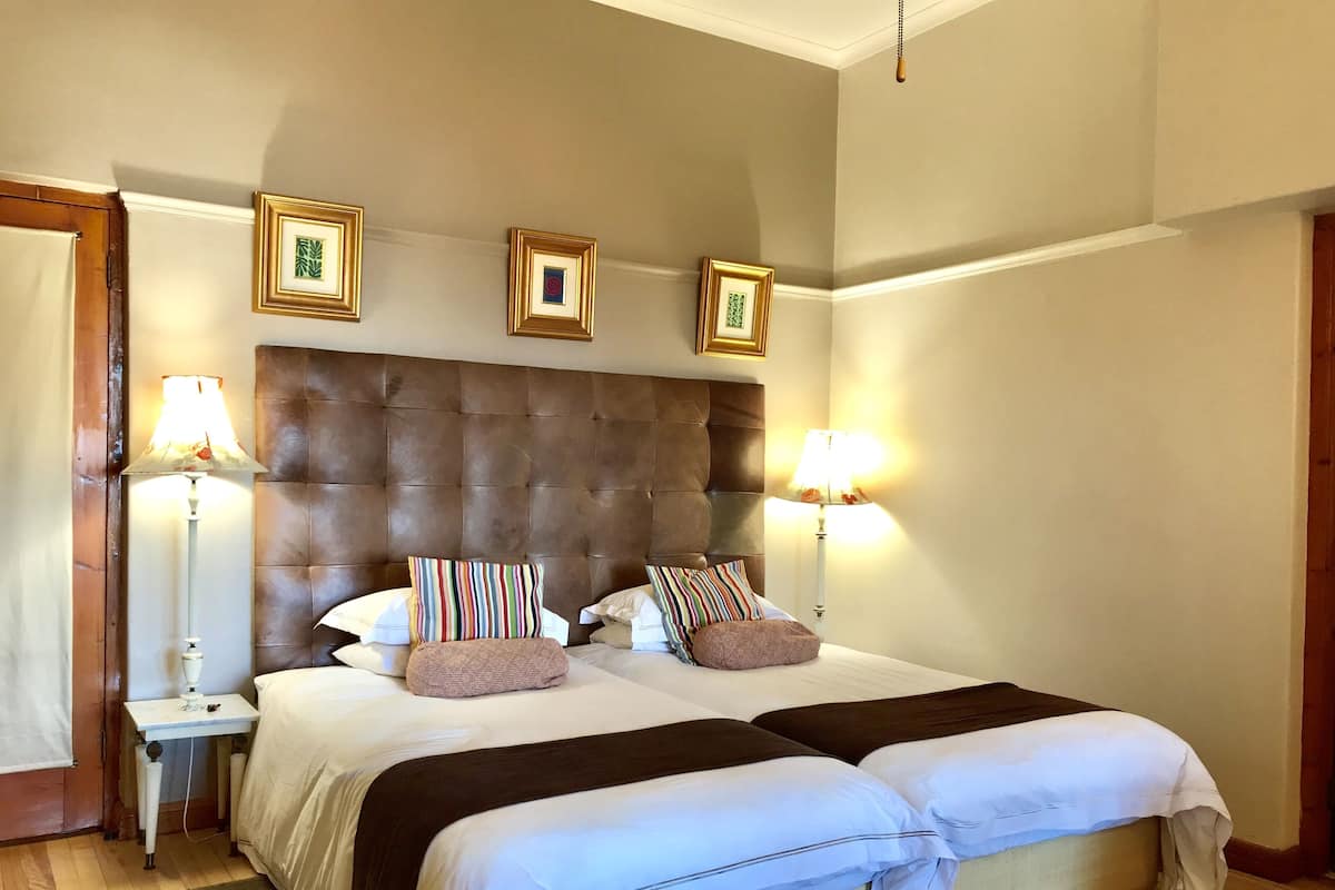 A double bed with a tufted headboard, two bedside tables with lamps, and three framed pictures on the wall.