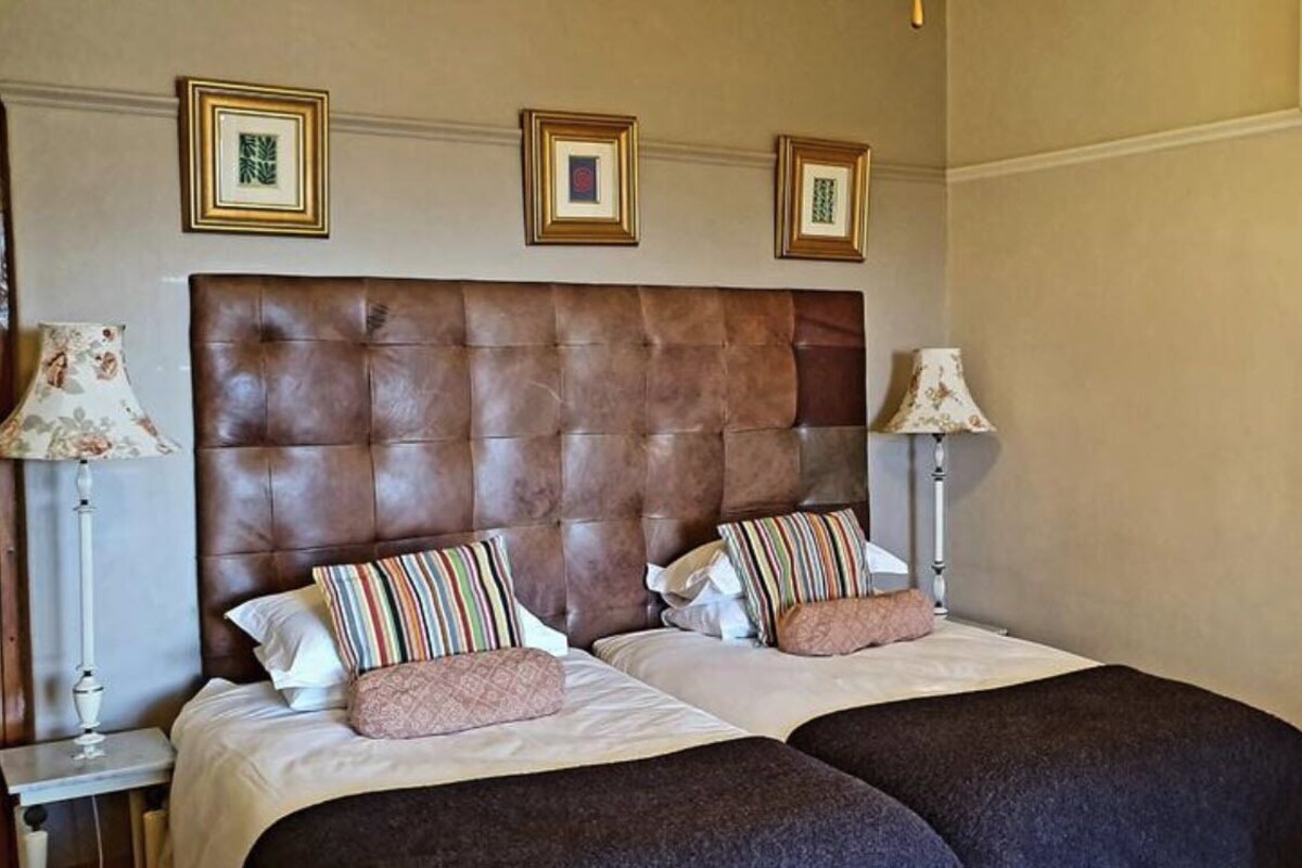 A double bed with a brown headboard, two bedside tables with lamps, and three framed pictures on the wall.