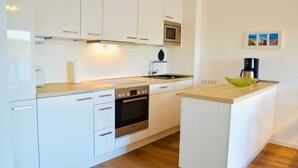 A modern kitchen with white cabinets, a built-in oven, a microwave, and a coffee maker. - Groyne 10 App No. 26 max 2 pers (+1 child 0-3 years) - 7/26 (Dierhagen)