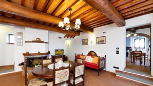 Un comedor con una mesa y sillas de madera, chimenea y candelabro.