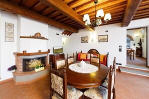 A dining area with a wooden table and chairs, a fireplace, and a chandelier.