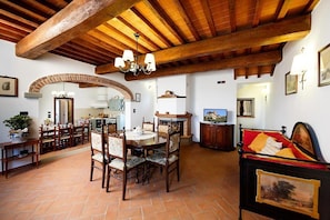 A dining area with a wooden table and chairs, a fireplace, and a television on the wall.