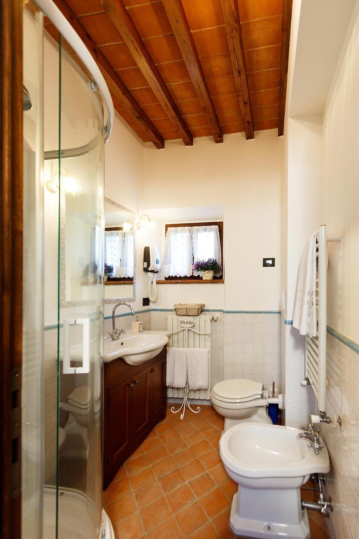 A bathroom with a glass shower enclosure, a sink, a bidet, and a toilet.