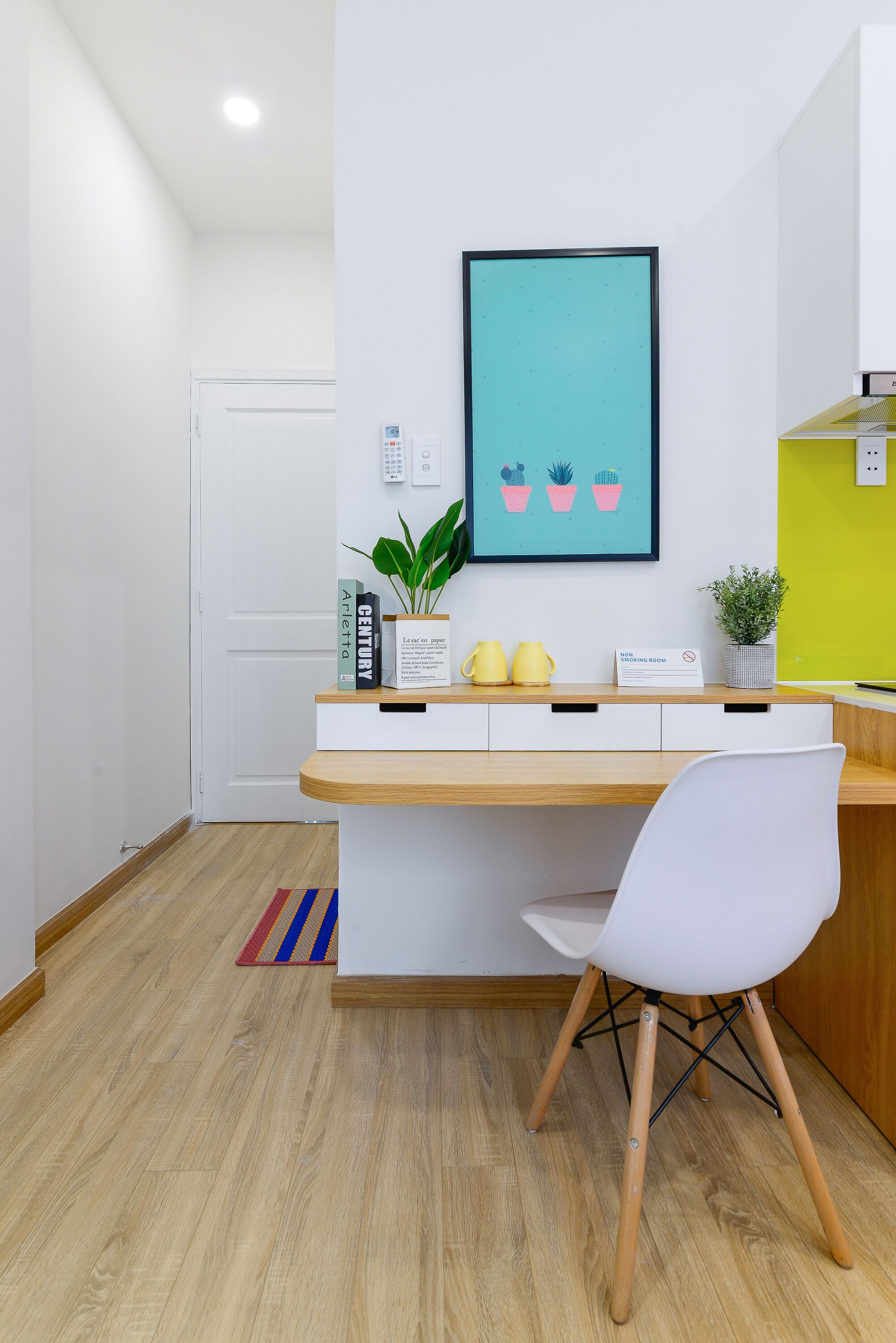 A modern office space with a wooden desk, white chair, and a framed artwork on the wall.