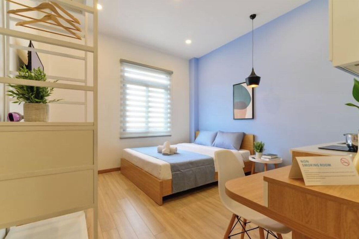 Un dormitorio moderno con cama, mesita de noche, silla y escritorio con un cartel de 'No Smoking'.