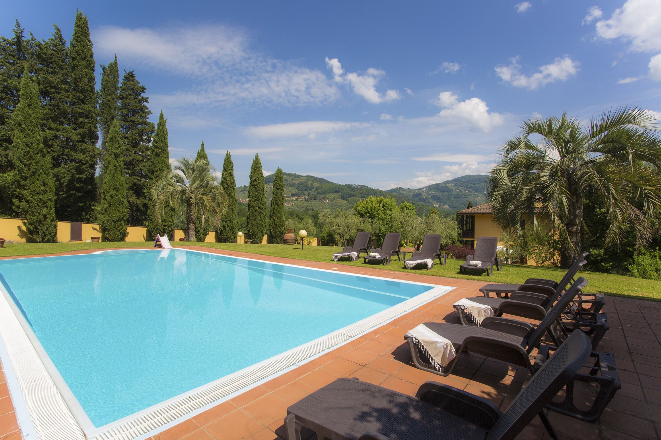 Piscina com espreguiçadeiras e vista da paisagem ao redor.