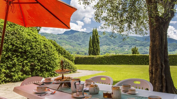 An outdoor dining area with a table set for tea, surrounded by greenery and a mountain view. - Villa / Independent home in Lucca with 4 bedrooms sleeps 8 (Lucca)