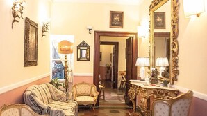 A room with a sofa, a chair, a table with a lamp, and a large ornate mirror. - Residenza Maritti Classic Rooms (Rome)