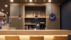 A bar area with wooden chairs, a counter, and a wall with bottles and a sign. - Holiday Inn Express Darmstadt by IHG (Darmstadt)