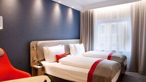 Une chambre d’hôtel avec deux lits, un bureau et une chaise.