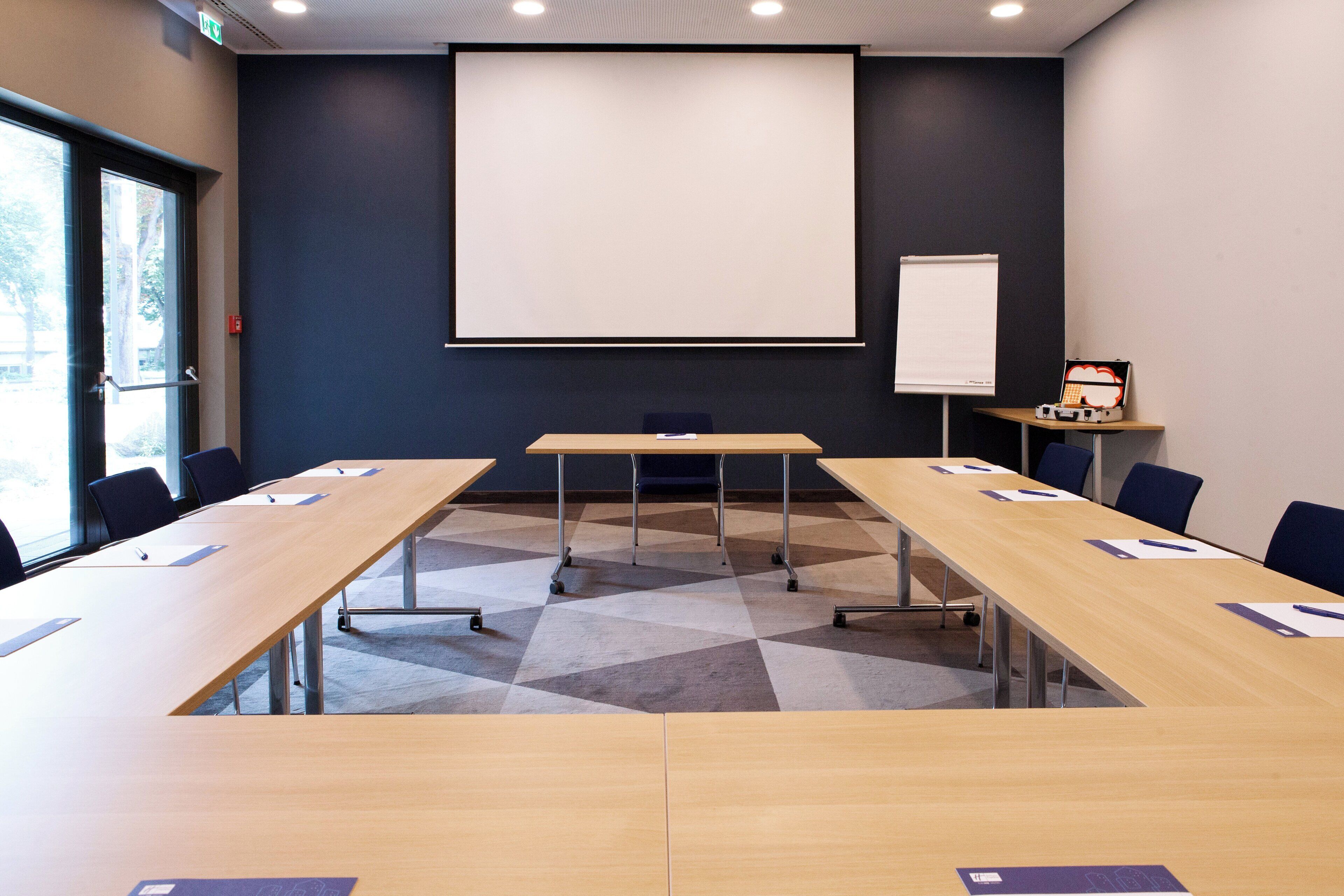 A conference room with a large screen, a whiteboard, and a projector on a stand.