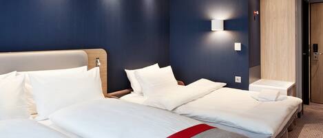 A hotel room with two beds, a wooden headboard, a wall-mounted light, and a wooden door.