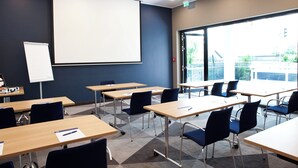 A conference room with multiple tables and chairs, a whiteboard, and a projector screen. - Holiday Inn Express Darmstadt by IHG (Darmstadt)