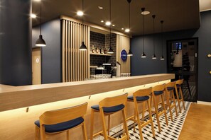 A bar area with wooden bar stools and pendant lighting. - Holiday Inn Express Darmstadt by IHG (Darmstadt)