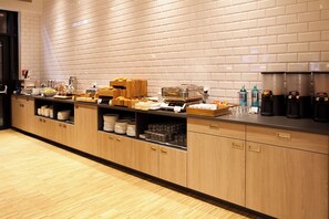 A buffet setup with various food items, glassware, and beverage dispensers.