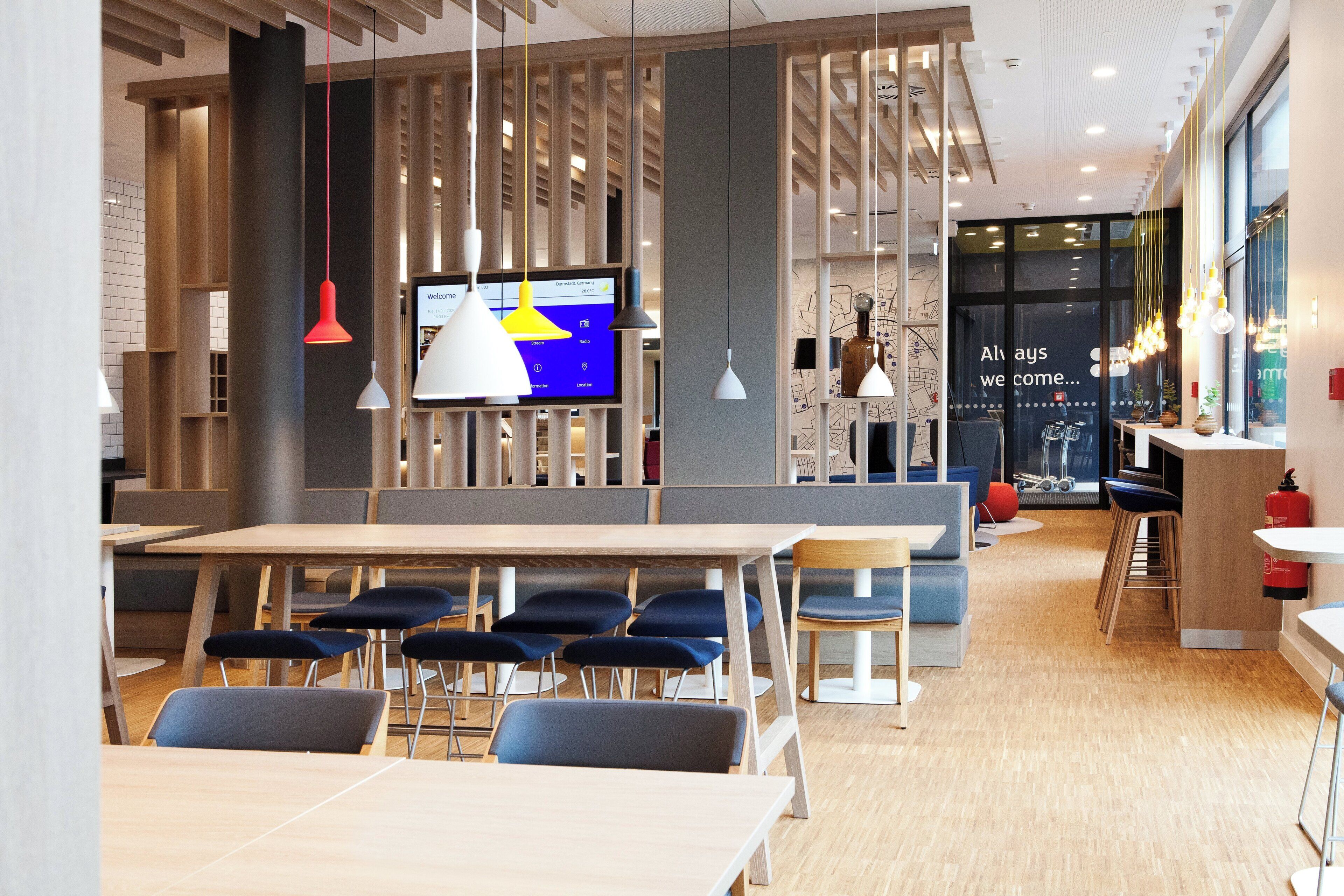 Un intérieur moderne avec une longue table à manger, des chaises bleues et des luminaires suspendus.