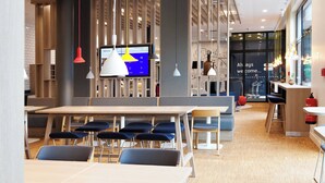 A modern interior with a long dining table, blue chairs, and pendant lighting. - Holiday Inn Express Darmstadt by IHG (Darmstadt)