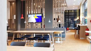 A modern interior with a long dining table, blue chairs, and pendant lighting.