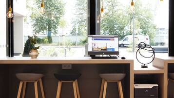 Zona de bar moderna con un monitor de computadora mostrando un sitio web, taburetes de madera y vistas a la calle.