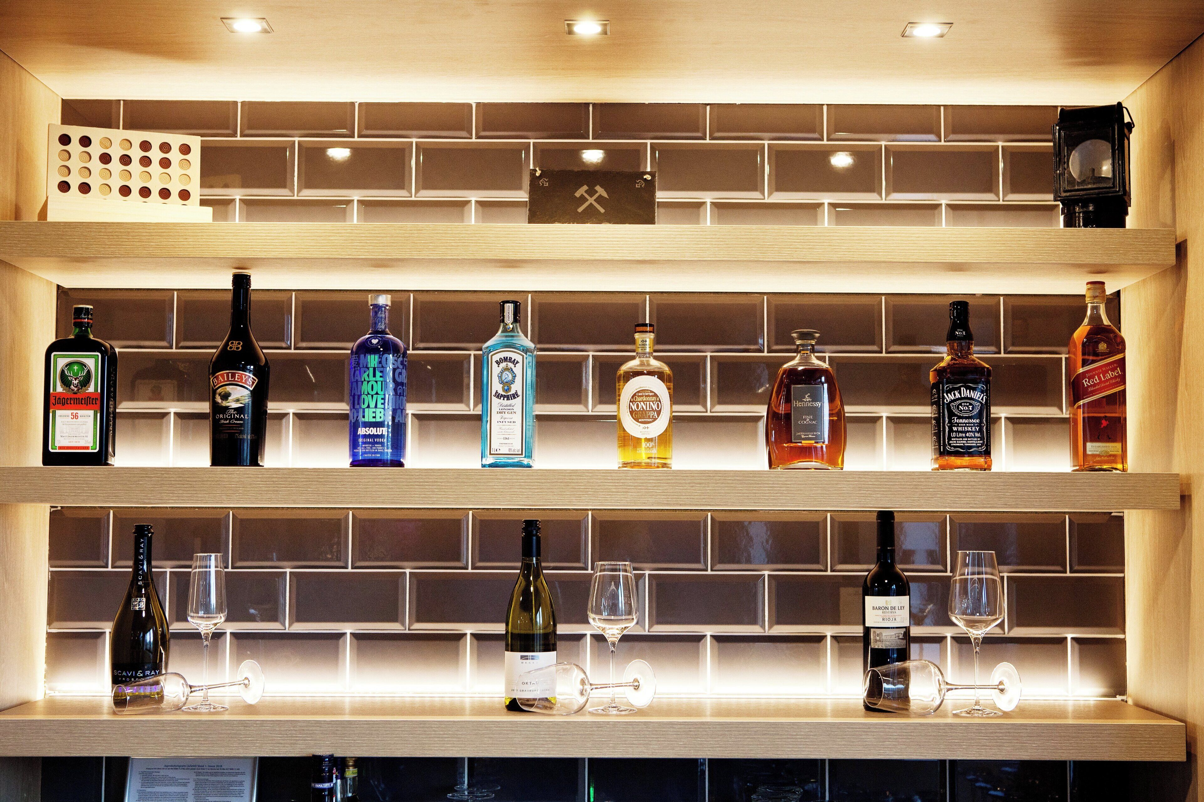 Uma área de bar com prateleiras cheias de garrafas de bebidas e copos.