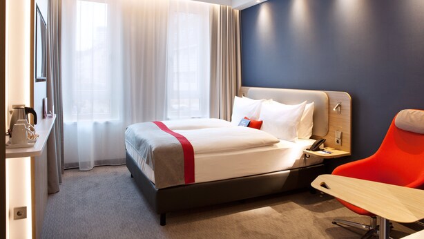 Une chambre d’hôtel avec un lit, un bureau et une chaise.