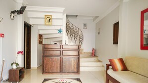 A spacious living area with a wooden cabinet, a sofa with a cushion, a staircase with a decorative railing, and a tiled floor. - My Way Cadde Butik Otel (Adalar)